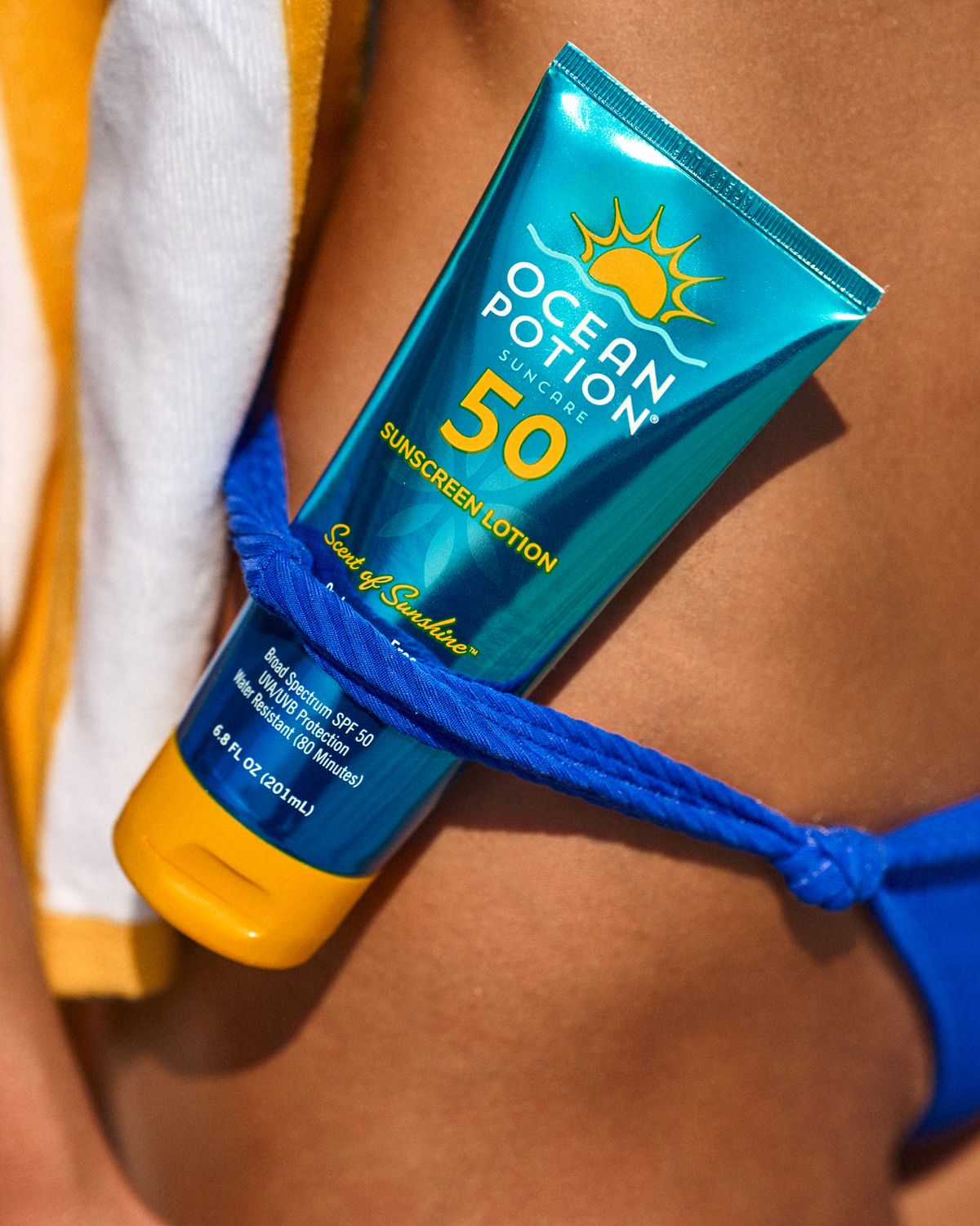 Close-up of sunscreen product against blue swimwear during a beach brand shoot in Miami, Florida.